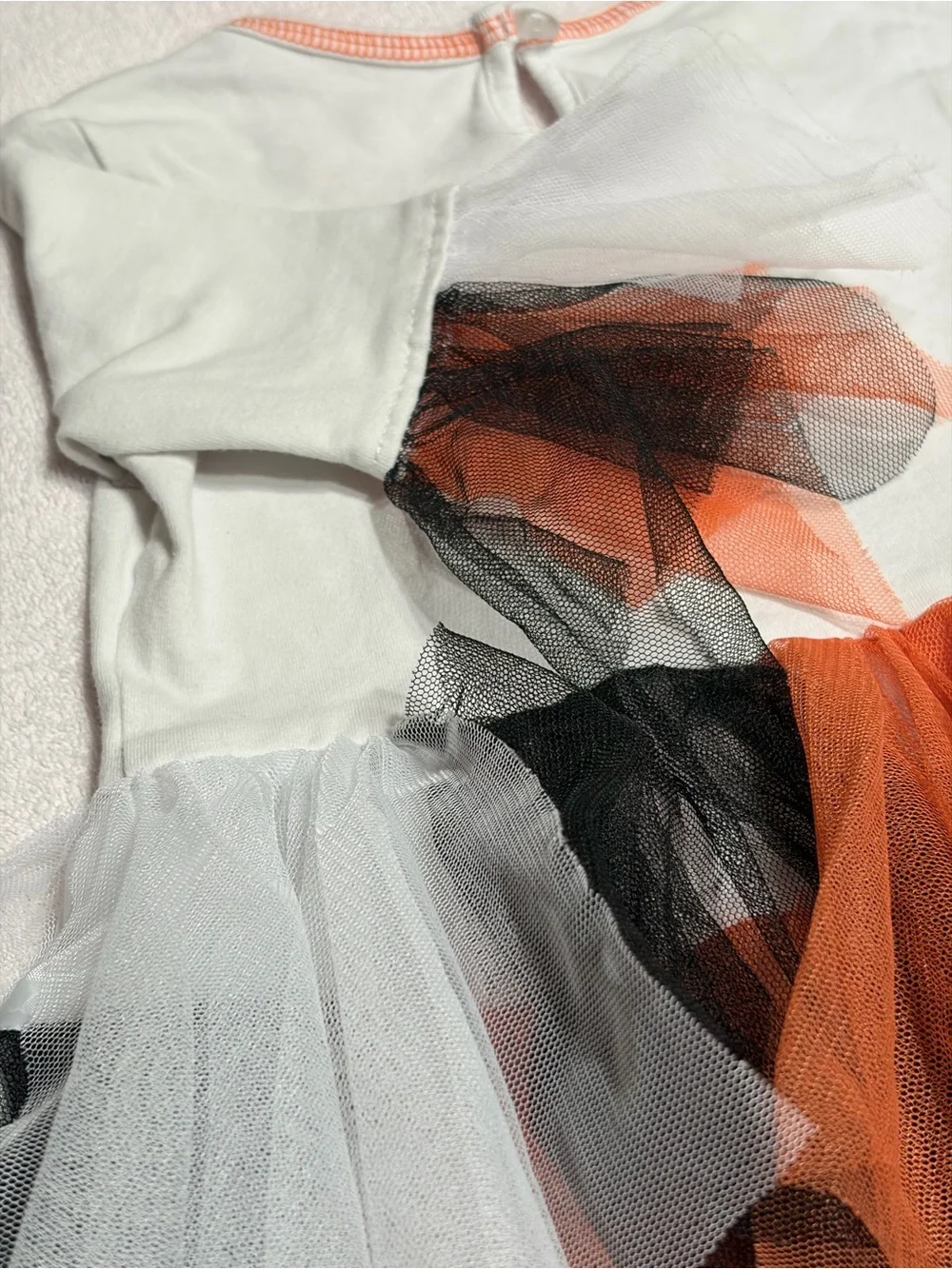 Cutie Halloween costume Has orange, black, and white tulle skirt and wrists.